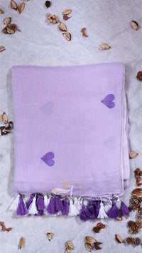 Lavender towel with heart patterns and tassels on a light gray background with decorative elements.