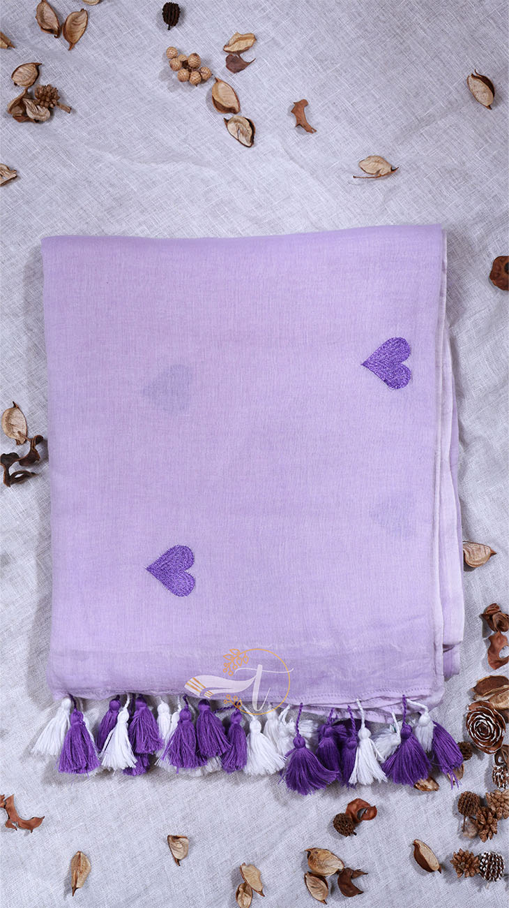 Lavender towel with heart patterns and tassels on a light gray background with decorative elements.