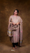 Woman wearing a traditional outfit with a shawl against a brown background