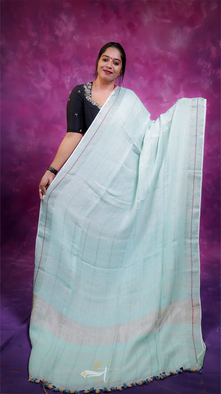 Woman wearing a light blue saree with a purple background