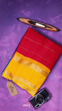 Red and yellow fabric with a wooden comb and camera on a purple background