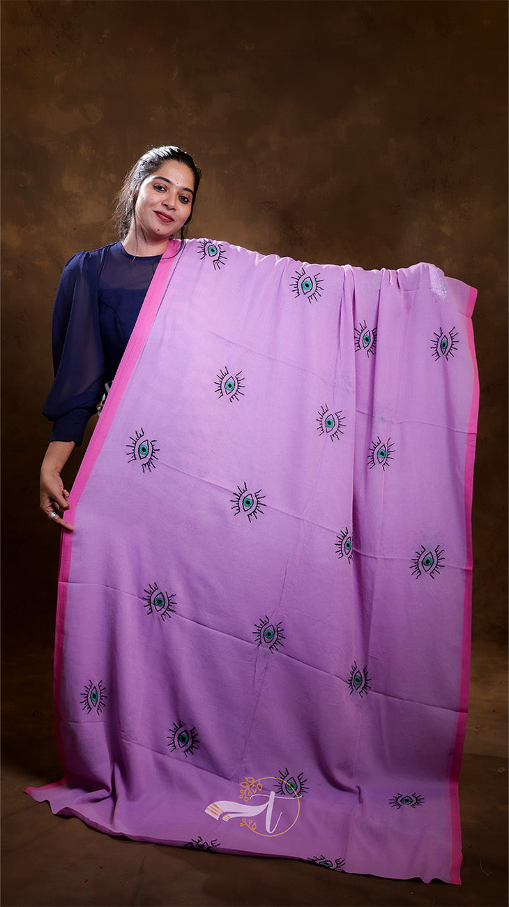 Woman holding a large pink saree with blue patterns against a brown background