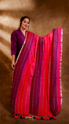 Woman wearing a vibrant red and pink saree with a plain background