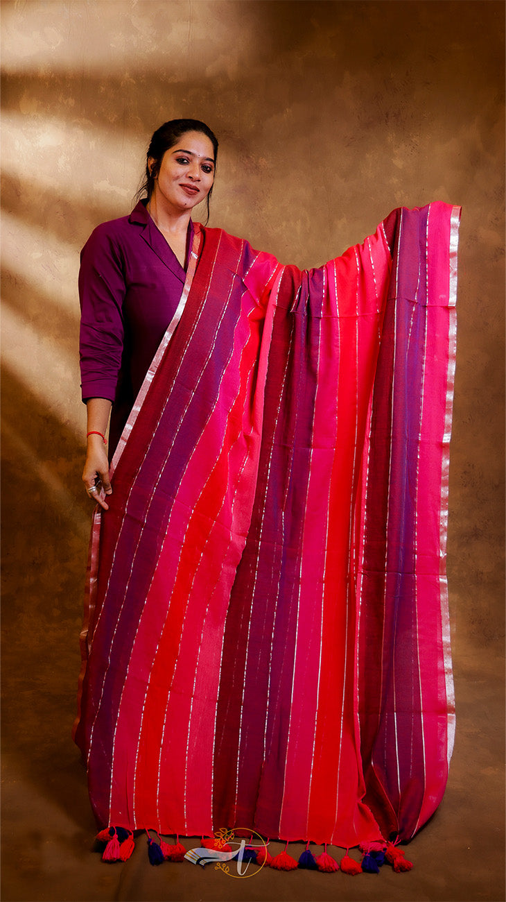 Woman wearing a vibrant red and pink saree with a plain background