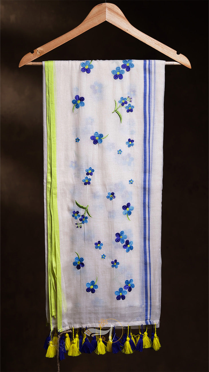 Scarf with floral patterns and tassels hanging on a wooden hanger against a dark background