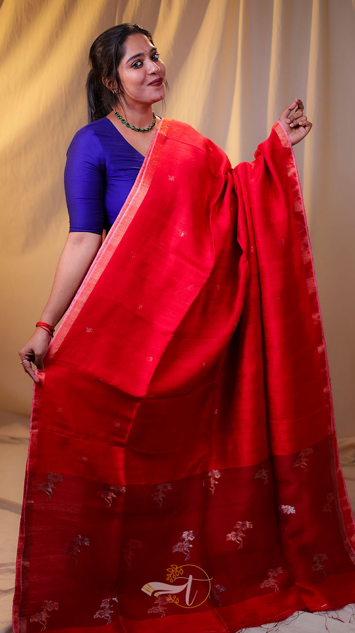Woman wearing a red saree with a blue blouse against a beige curtain background