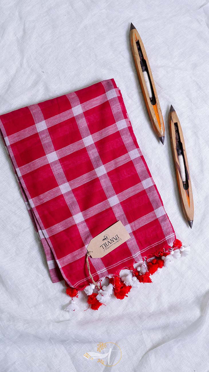 Red checkered towel with tassels and a pen on a white background