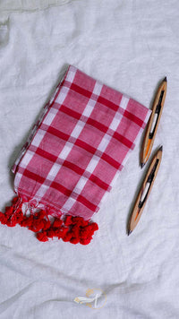 Red and white checkered towel with tassels on a light gray background