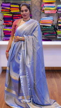 Woman wearing a blue saree with a colorful background of fabric.