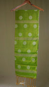 Green scarf with white polka dots and gold fringe on a beige background