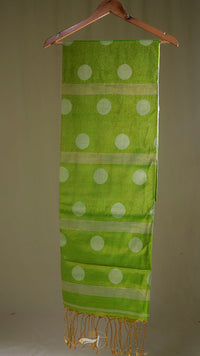 Green scarf with white polka dots and gold fringe on a beige background