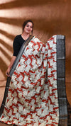 Woman wearing a saree with a red and white pattern against a brown background