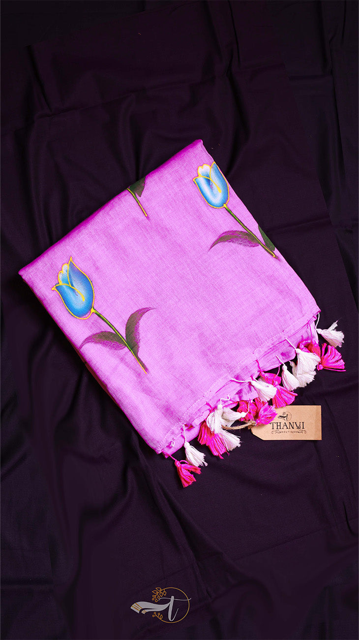 Pink scarf with floral designs and tassels on a dark purple fabric background