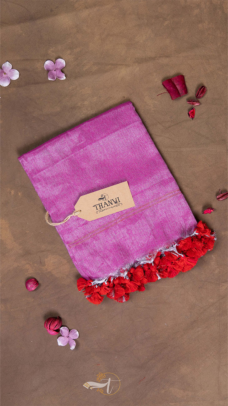 Pink fabric with red fringes and a brand tag on a brown background