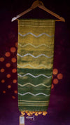 Green and yellow patterned fabric on a hanger against a dark background