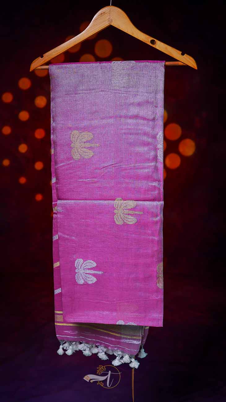 Pink saree with white patterns and tassels on a wooden hanger against a dark background.