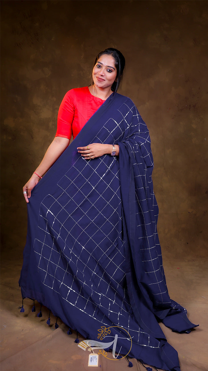 Woman wearing a blue saree with white patterns on a brown background