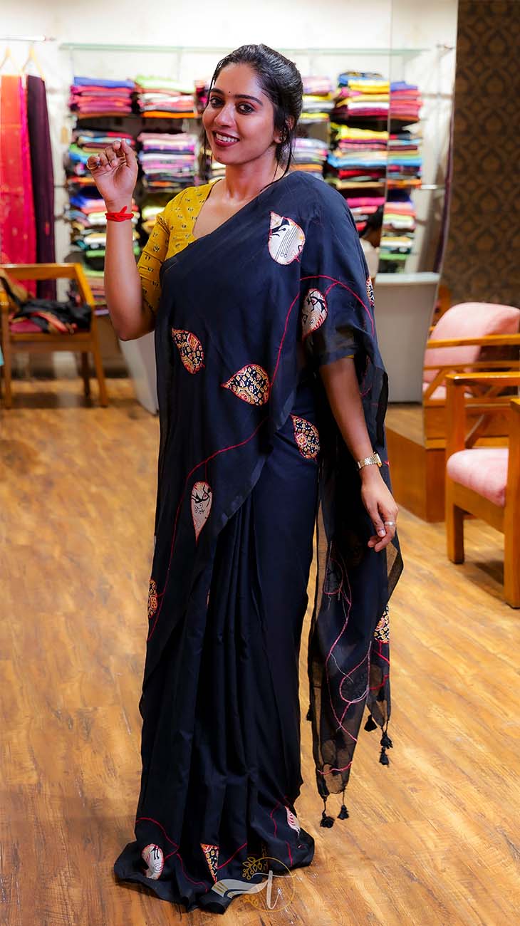 Woman in a black saree with gold patterns in a store setting