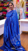 Woman wearing a blue saree with a colorful background of fabric