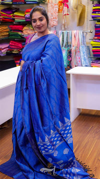 Woman wearing a blue saree with a colorful background of fabric