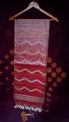 Textile with zigzag pattern hanging on a wooden hanger against a dark background