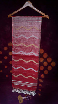 Textile with zigzag pattern hanging on a wooden hanger against a dark background