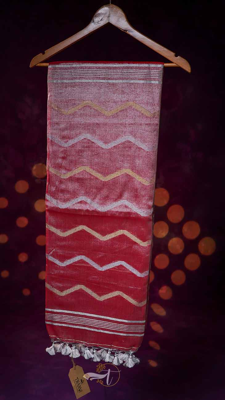 Textile with zigzag pattern hanging on a wooden hanger against a dark background