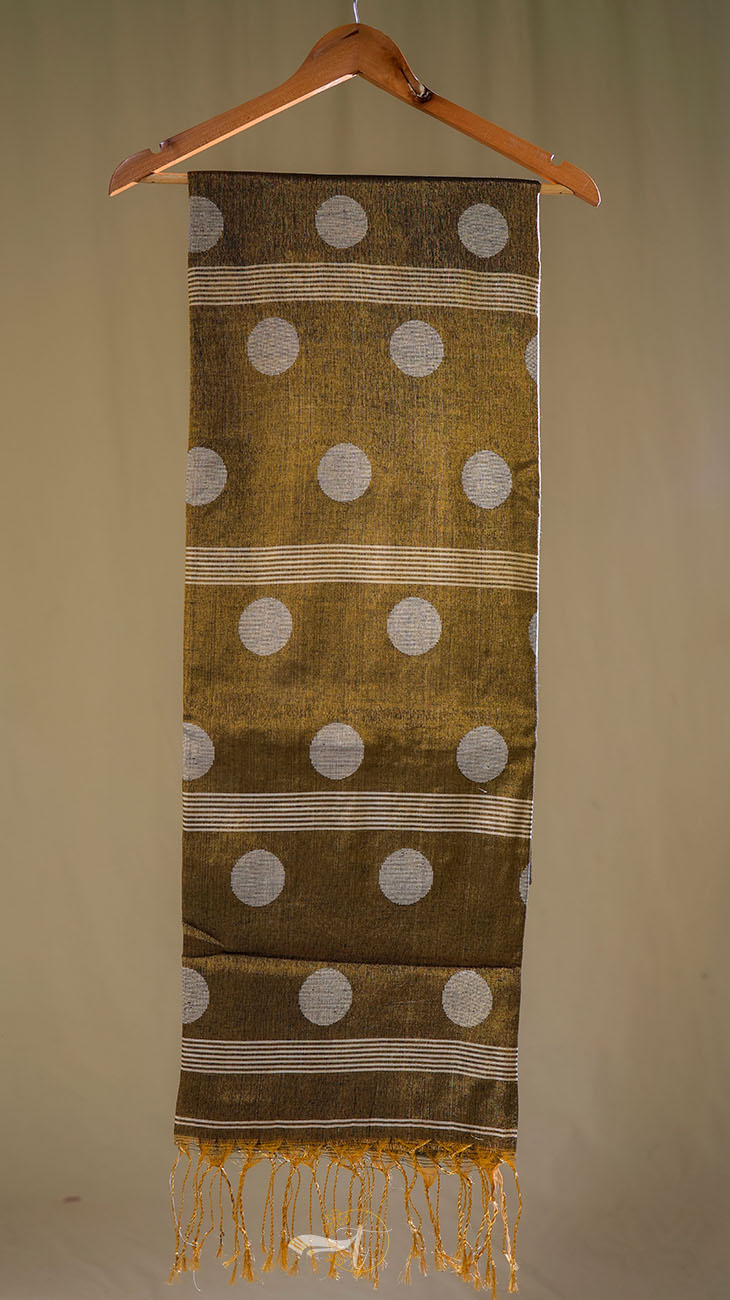 Textile with white polka dots and fringes on a wooden hanger against a beige background