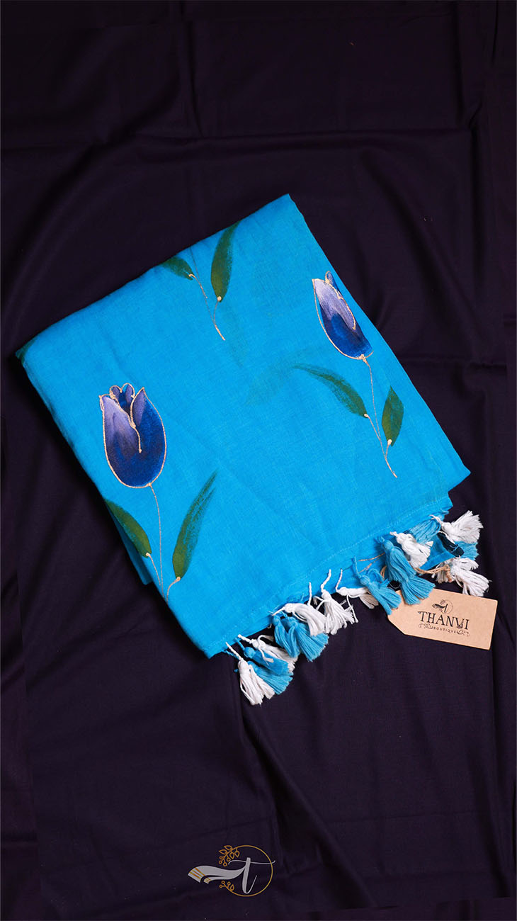 Blue scarf with floral patterns and tassels on a dark fabric background