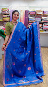Woman holding a blue saree with a pattern in a store setting