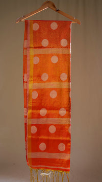 Orange scarf with white polka dots hanging on a wooden hanger against a beige background