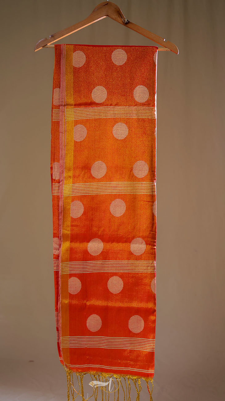 Orange scarf with white polka dots hanging on a wooden hanger against a beige background
