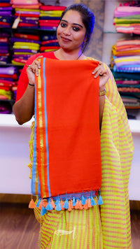 Woman holding a colorful scarf with a vibrant background of fabric samples.
