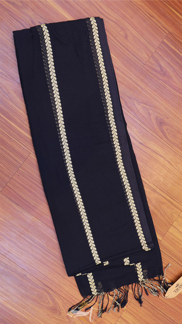 Black scarf with gold trim on a wooden surface