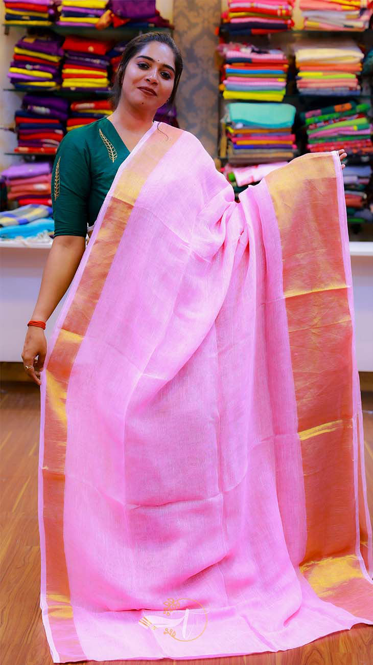 Woman holding a pink saree with a colorful background of folded fabrics