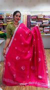 Woman holding a pink saree with a pattern in a fabric store.