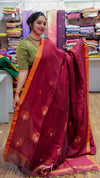 Woman holding a red saree with a green blouse in a fabric store.