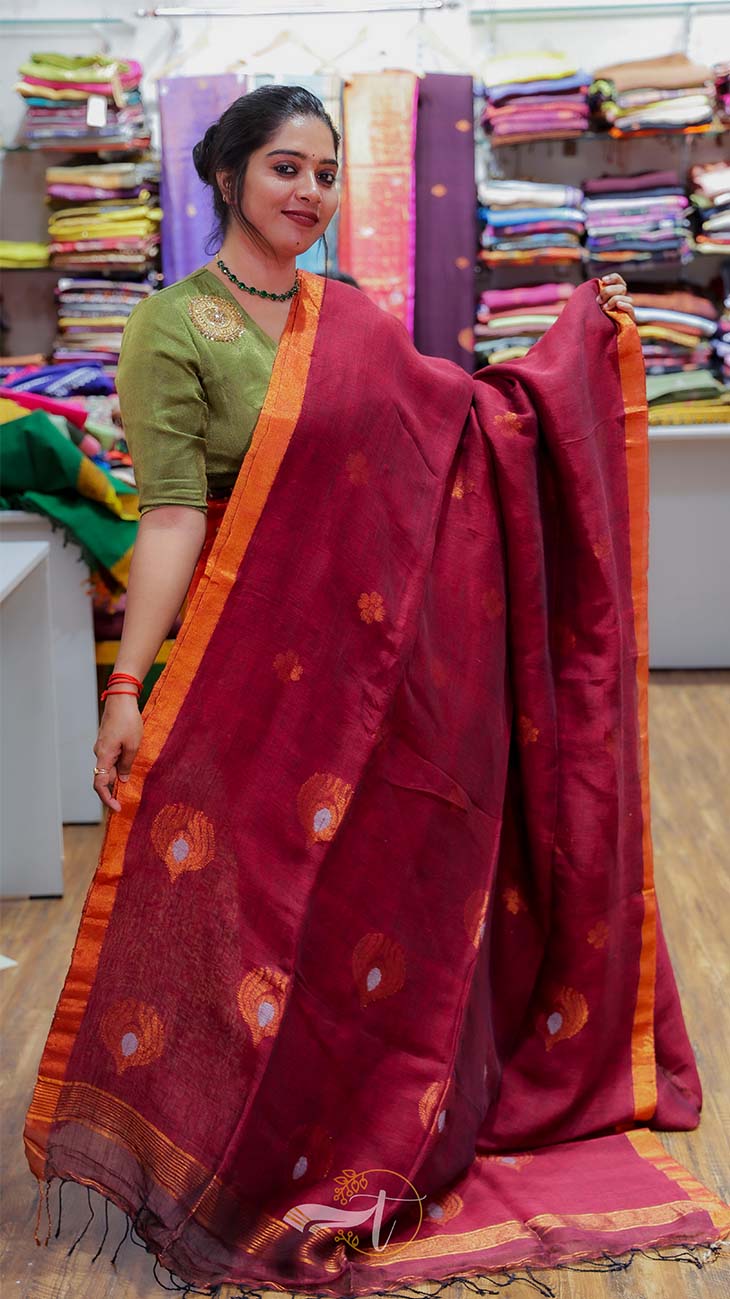 Woman holding a red saree with a green blouse in a fabric store.