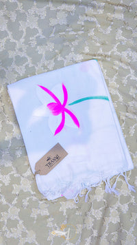White towel with pink palm tree design on a textured surface