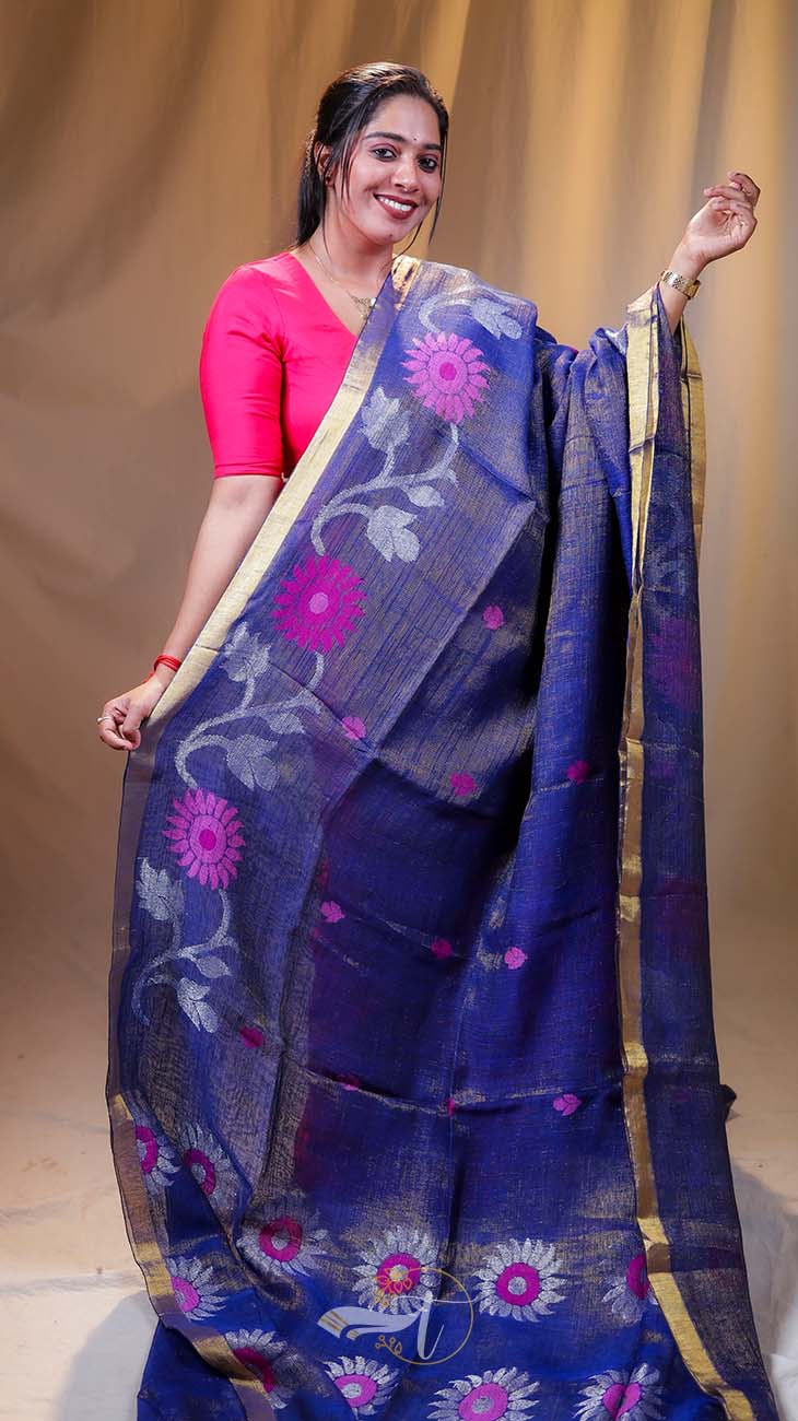 Woman wearing a blue saree with floral patterns against a plain background