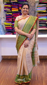 Woman wearing a traditional saree in a store setting with colorful fabrics in the background.