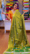 Woman holding a green saree with a floral pattern in a fabric store.