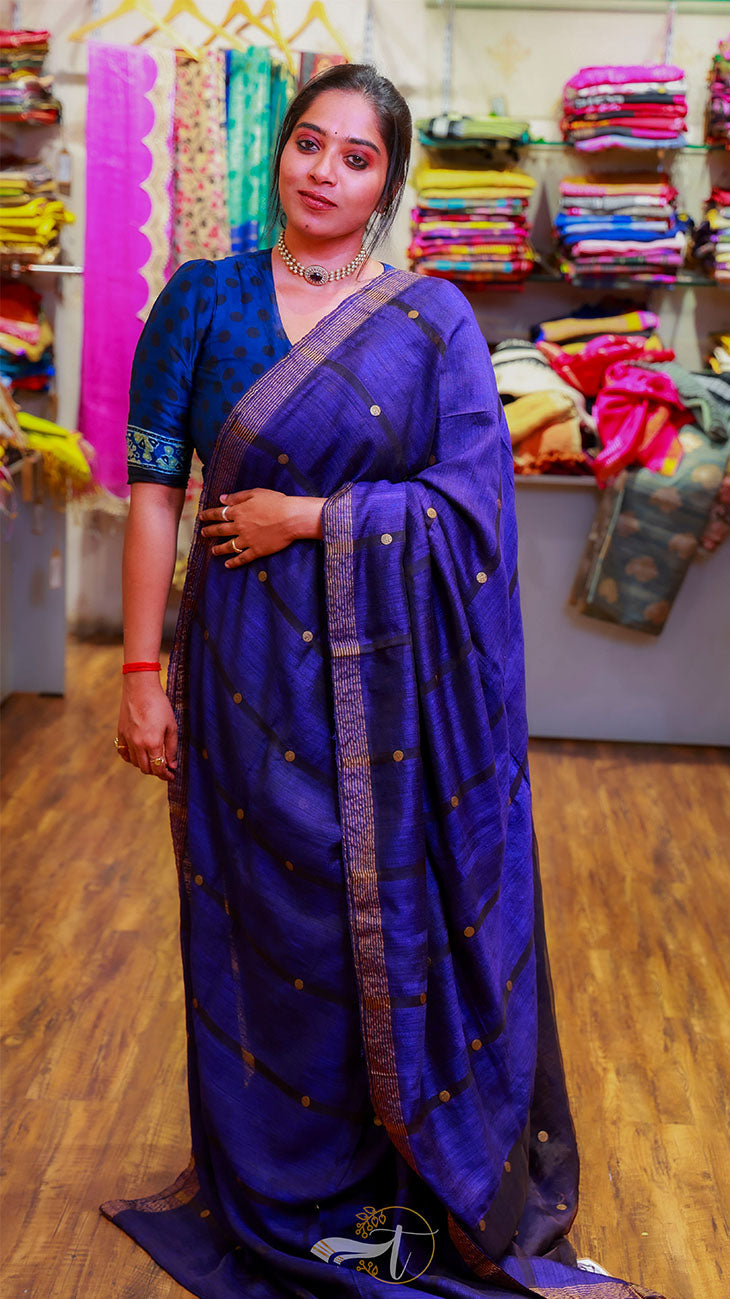 Woman wearing a blue saree with a patterned border in a store setting.