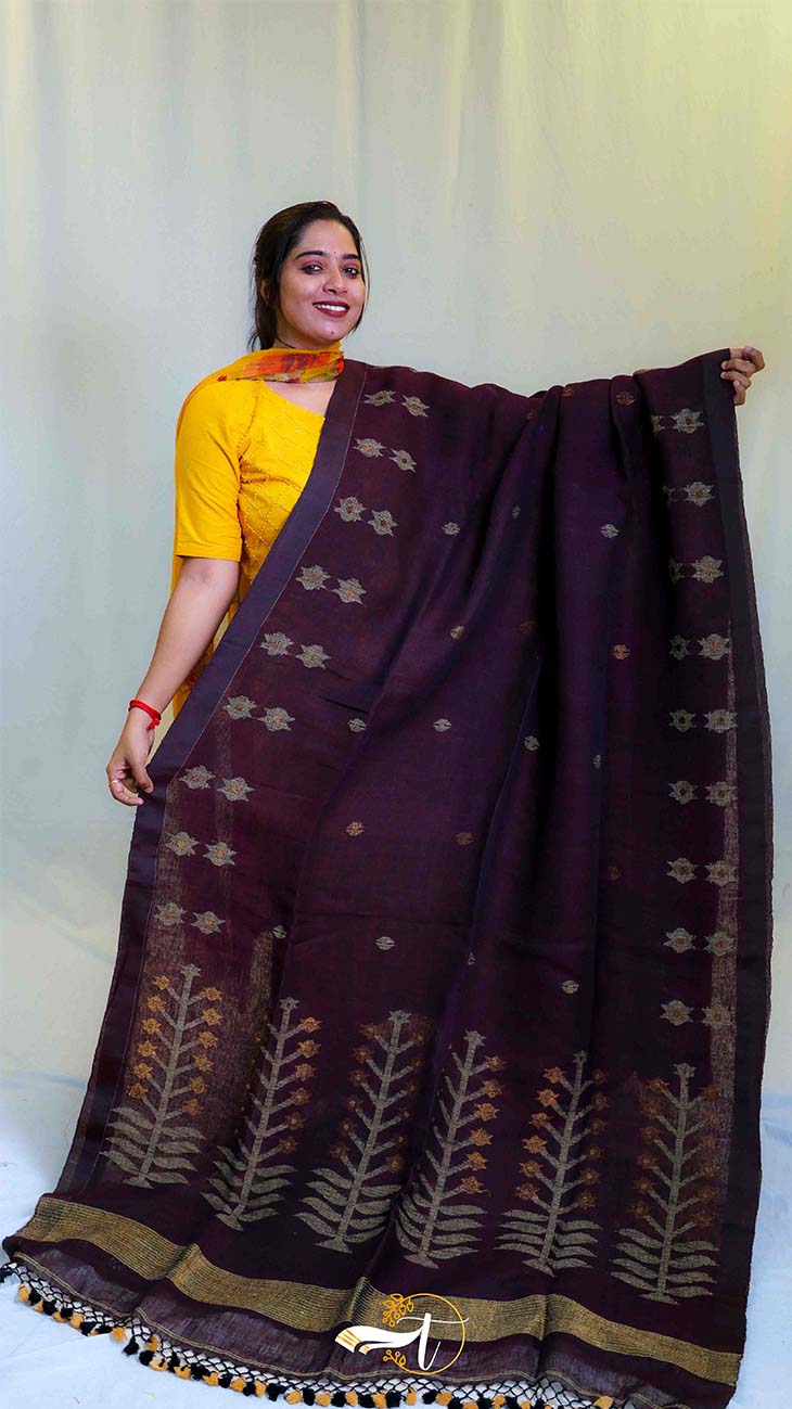 Woman holding a dark purple saree with floral patterns against a white background