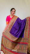 Woman wearing a colorful saree with a purple blouse against a white background