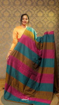 Woman holding a colorful striped saree against a patterned wall.