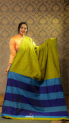 Woman holding a green and blue striped fabric against a patterned wall.