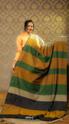 Woman holding a multicolored striped fabric against a patterned wall.