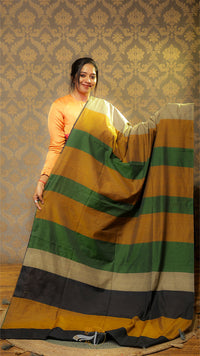 Woman holding a multicolored striped fabric against a patterned wall.