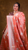 Woman wearing a peach saree with a gold border against a brown background
